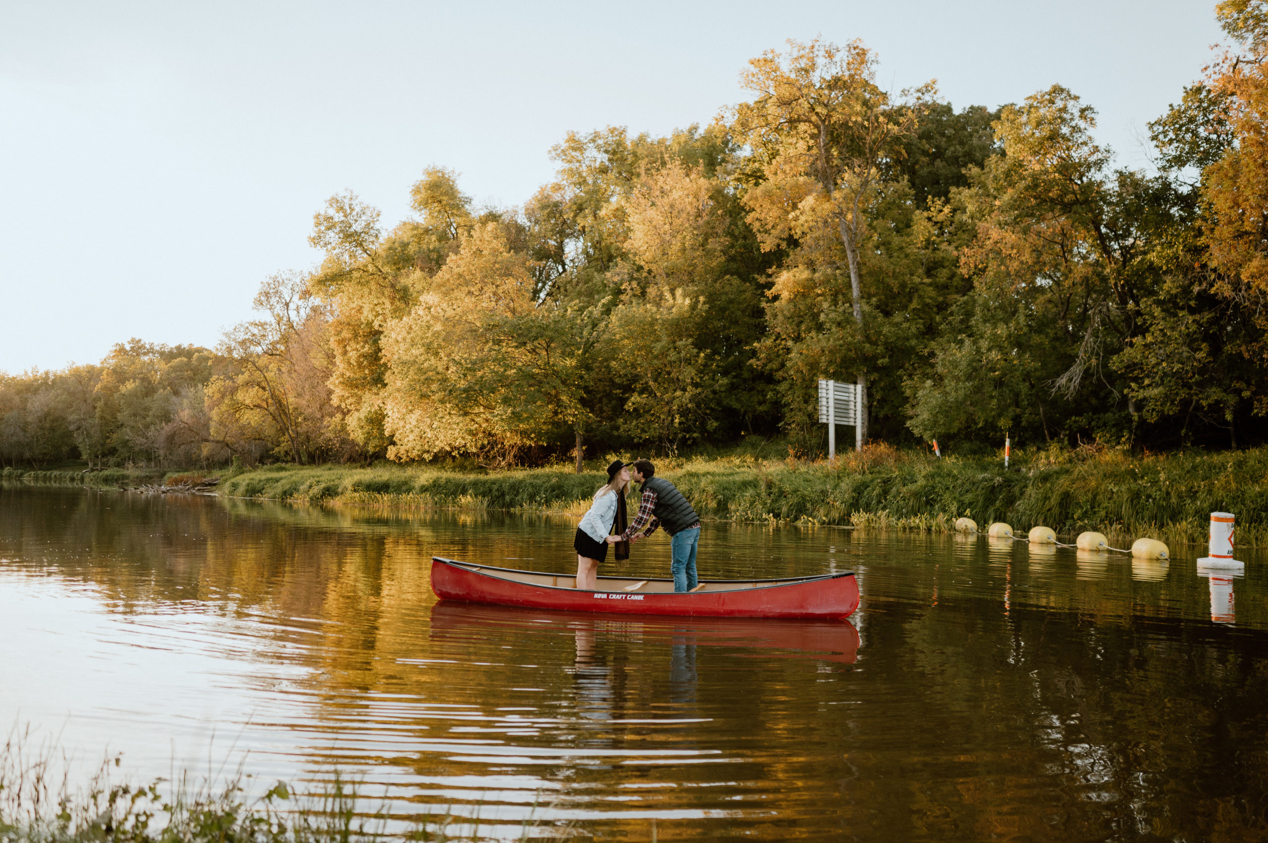 Couple kiss standing up in their canoe during an engagement session