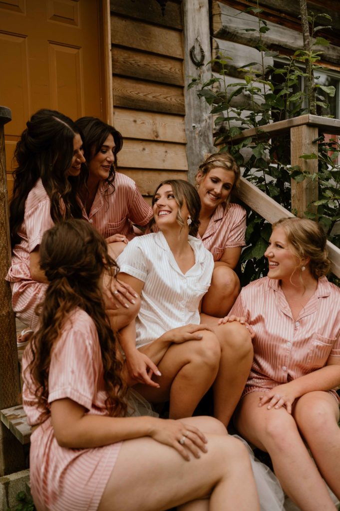 A bride enjoys time with her bridesmaids in front of a cabin