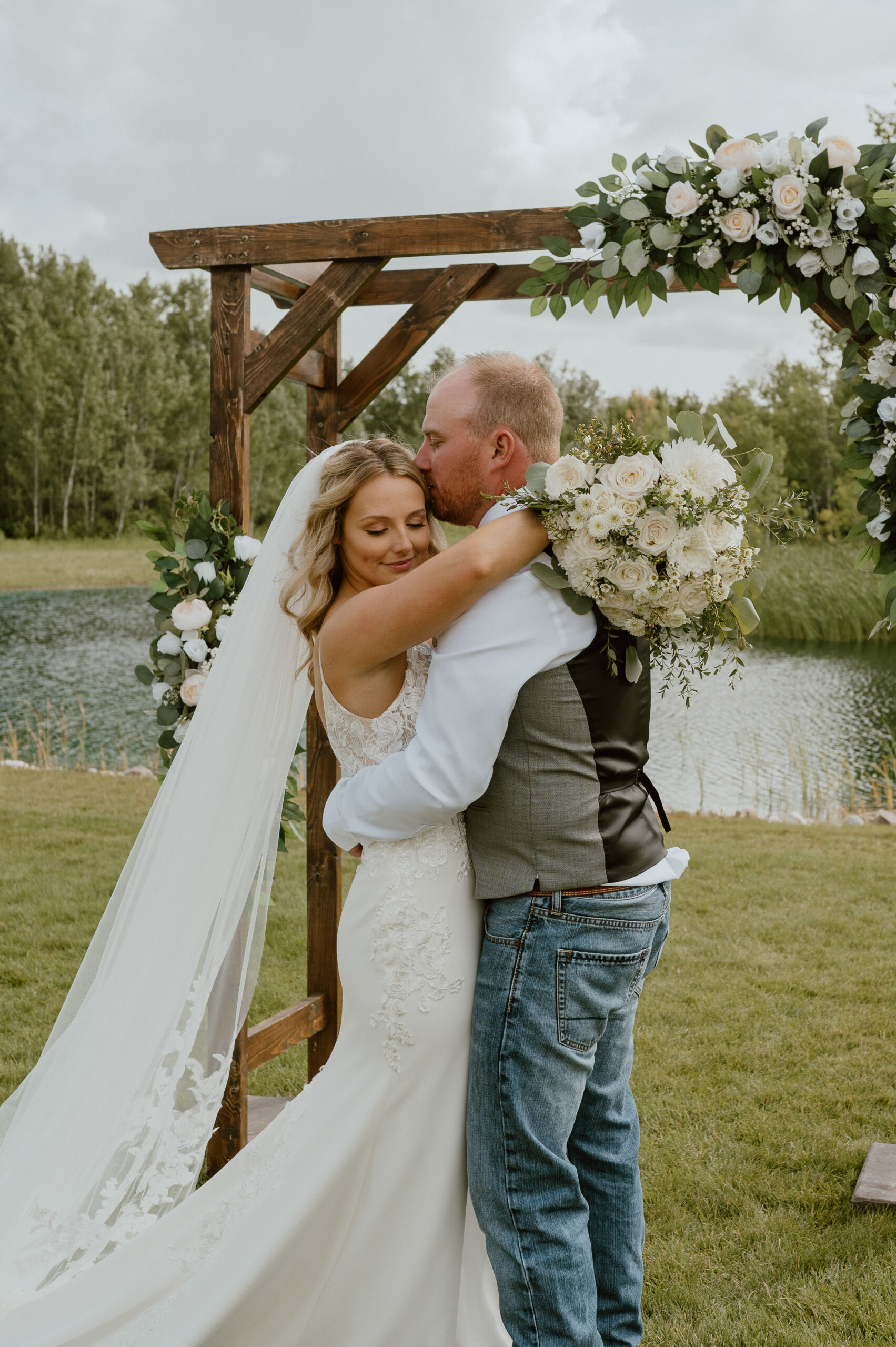 Groom kisses his bride on the forehead at the altar at The White Poplar in Manitoba